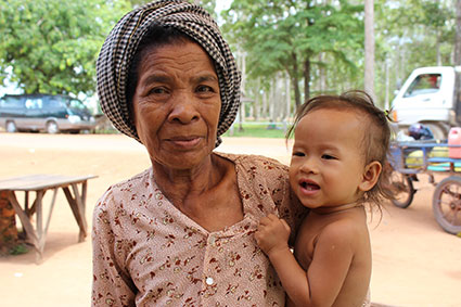 Una mujer sostiene en brazos un niño en una zona de puestos de comida de carretera, cerca del complejo de Angkor (Camboya).