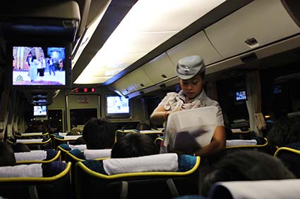 La azafata del autobús Gold Class que nos llevó de Chiang Mai a Bangkok reparte snacks a los pasajeros (Tailandia). 