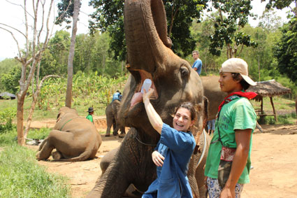 Un eleefante bebe agua de una botella de una turista en el campamento Baan Chang, en Chiang Mai.