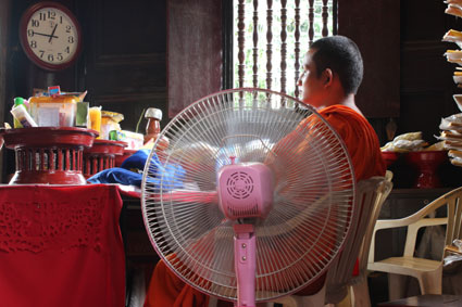 Un monje budista se refresca con un ventilador en un templo en Chiang Mai, Tailandia.