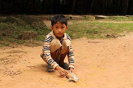 Un niño juega con un coche hecho con una botella de plástico entre los templos de Angkor Wat (Camboya).