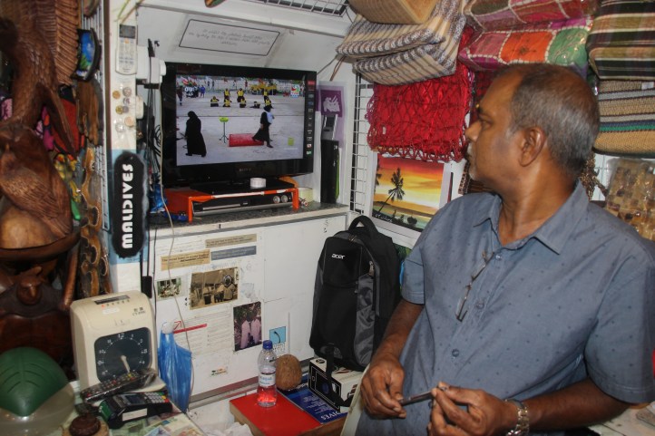 El dependiente de la tienda de souvenirs mira entretenido el partido de este particular deporte en la pantalla de su televisión, Malé (Maldivas)
